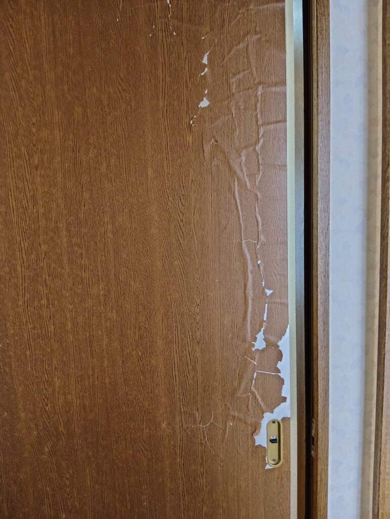 築30年戸建住宅の室内ドア。表面の化粧シートが浮き、割れてボロボロになっている施工前の状態