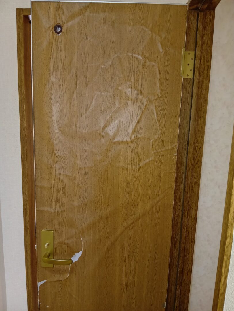 築30年戸建住宅の室内ドア。表面の化粧シートが浮き、割れてボロボロになっている施工前の状態