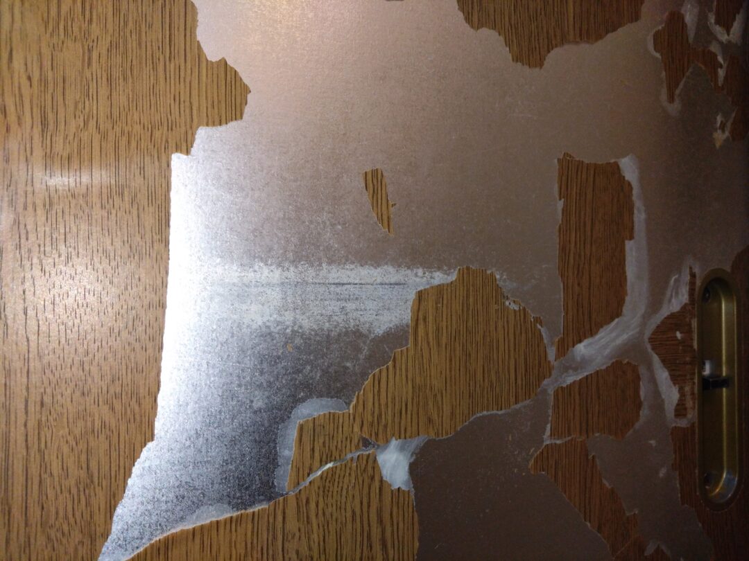 築30年戸建住宅の室内ドア。表面の化粧シートが浮き、割れてボロボロになっている施工前の状態