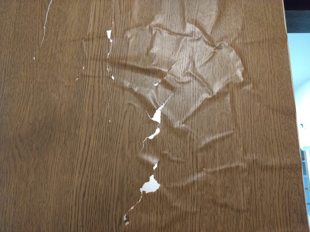 築30年戸建住宅の室内ドア。表面の化粧シートが浮き、割れてボロボロになっている施工前の状態